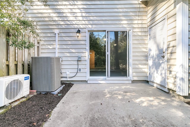 view of exterior entry featuring central AC unit, ac unit, and a patio area