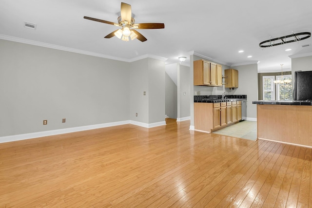 kitchen with light brown cabinets, black fridge, light wood-type flooring, ornamental molding, and sink