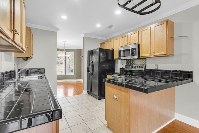 kitchen with light tile patterned floors, kitchen peninsula, stainless steel appliances, tile counters, and sink