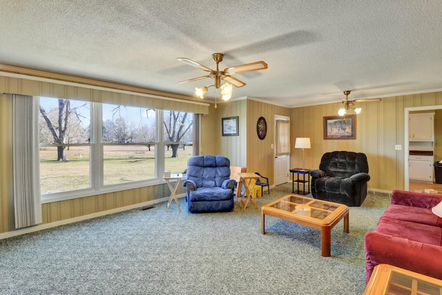 living room with carpet flooring, a textured ceiling, ceiling fan, and ornamental molding