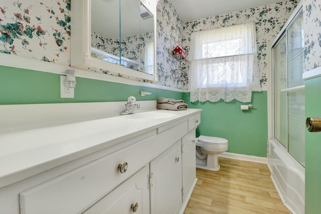 full bathroom with toilet, enclosed tub / shower combo, wood-type flooring, and vanity