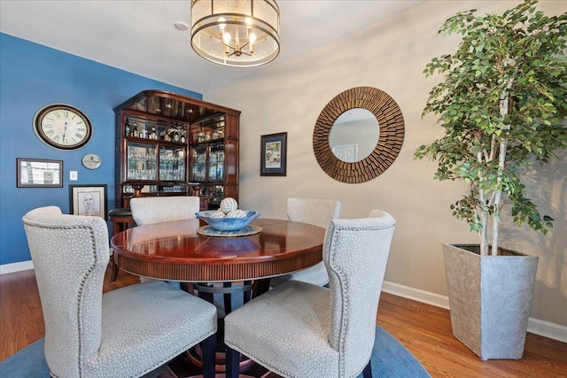 dining area with a notable chandelier, baseboards, and wood finished floors