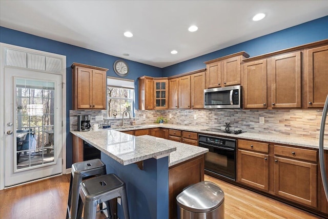 kitchen featuring black appliances, a breakfast bar area, a sink, and brown cabinets