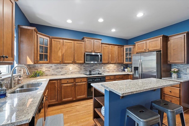 kitchen featuring black appliances, a breakfast bar area, a sink, and brown cabinetry