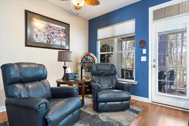 living area with ceiling fan, baseboards, and wood finished floors