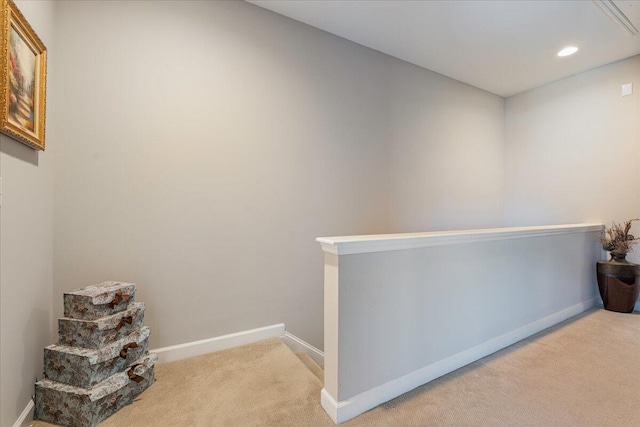 corridor with baseboards, an upstairs landing, and light colored carpet