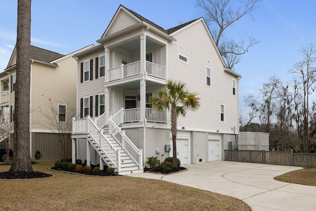 view of front of house with driveway, a garage, a balcony, stairs, and a front lawn