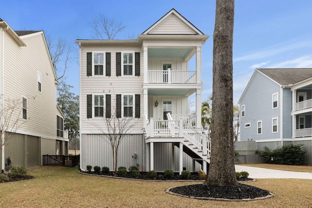 beach home with a balcony, a porch, board and batten siding, and a front yard