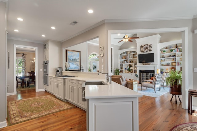 3948 Gift Blvd, Johns Island, SC 29455 - kitchen featuring a sink, a peninsula, light countertops, crown molding, and light wood-style flooring