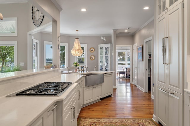 3948 Gift Blvd, Johns Island, SC 29455 - kitchen featuring stainless steel gas cooktop, white cabinets, light wood-style flooring, ornamental molding, and light countertops