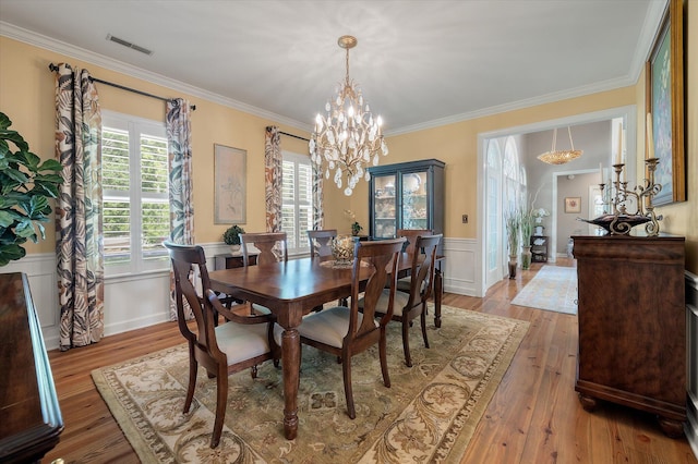 3948 Gift Blvd, Johns Island, SC 29455 - dining space with a chandelier, wainscoting, crown molding, light wood-style floors, and a decorative wall