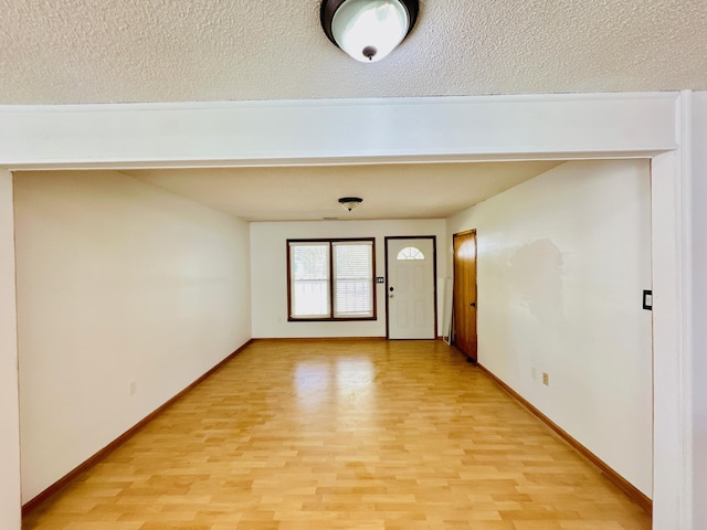 unfurnished room with a textured ceiling and light hardwood / wood-style flooring