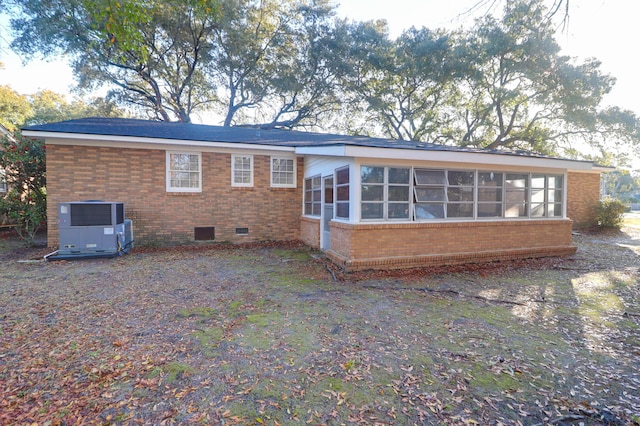 rear view of property featuring a sunroom, brick siding, central AC, and crawl space