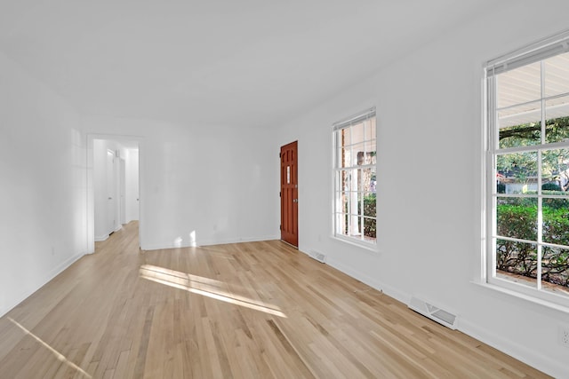 spare room featuring visible vents, plenty of natural light, and light wood-style flooring