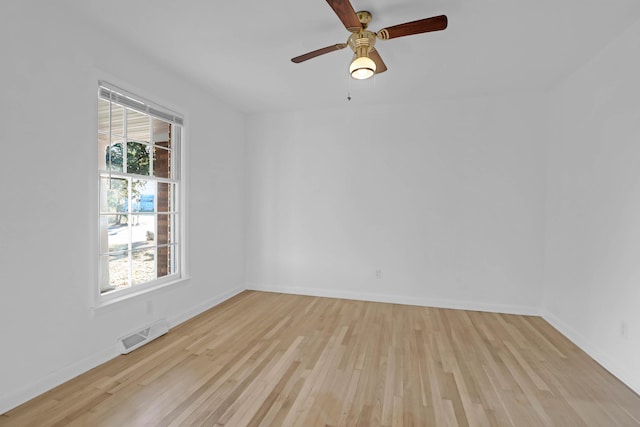 empty room with light wood finished floors, visible vents, a ceiling fan, and baseboards