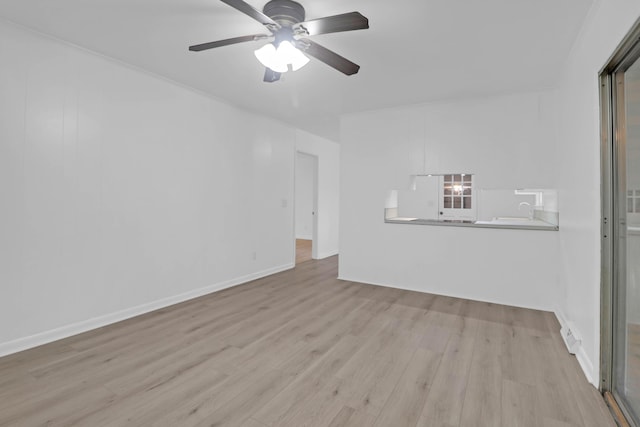 spare room featuring ceiling fan, baseboards, wood finished floors, and a sink