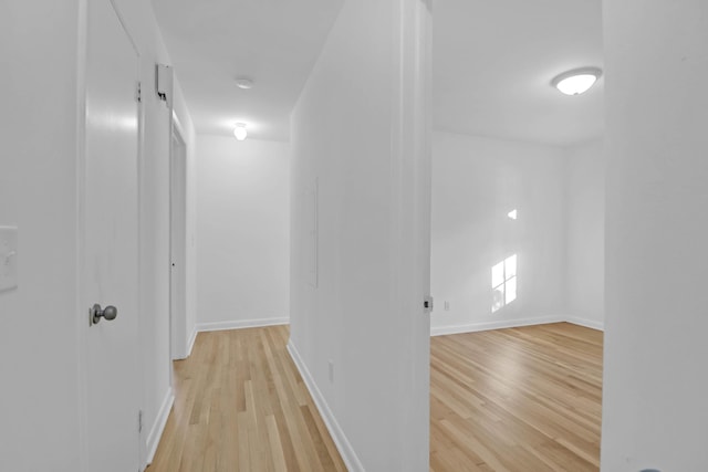 corridor with light wood-type flooring and baseboards