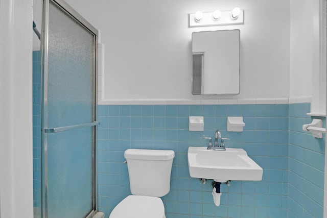 full bathroom featuring a sink, a wainscoted wall, toilet, and a shower stall