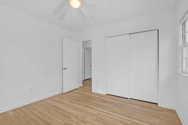 unfurnished bedroom with light wood finished floors, a closet, a ceiling fan, and baseboards