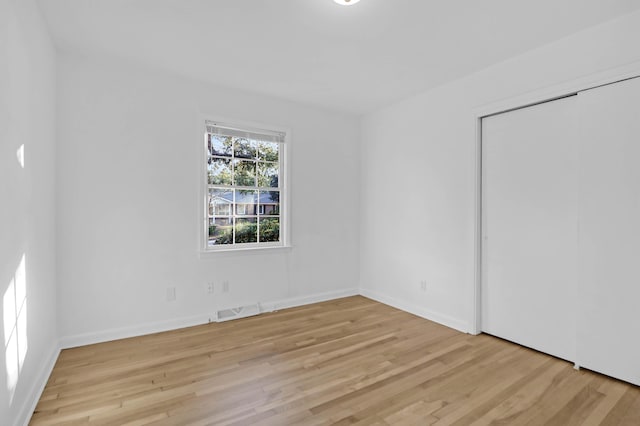 empty room featuring visible vents, baseboards, and wood finished floors