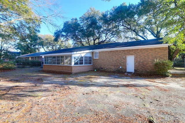 back of property with brick siding and a sunroom