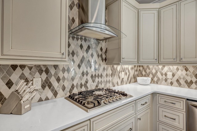 kitchen with light countertops, wall chimney range hood, cream cabinetry, and appliances with stainless steel finishes