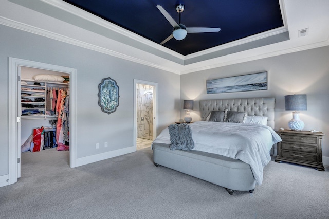 bedroom featuring carpet floors, a walk in closet, and a raised ceiling
