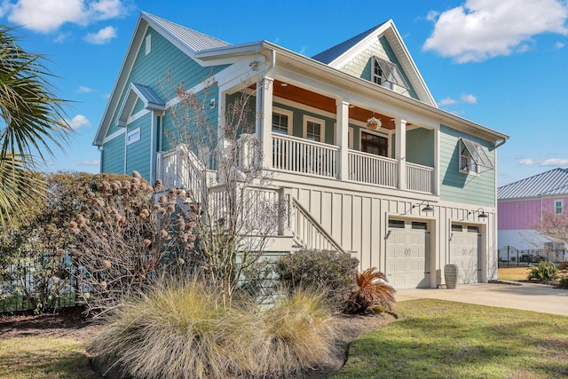 view of front of home with a front yard, concrete driveway, a garage, board and batten siding, and a porch