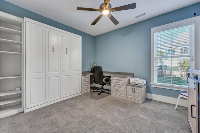 office space featuring carpet flooring, built in features, baseboards, visible vents, and ceiling fan