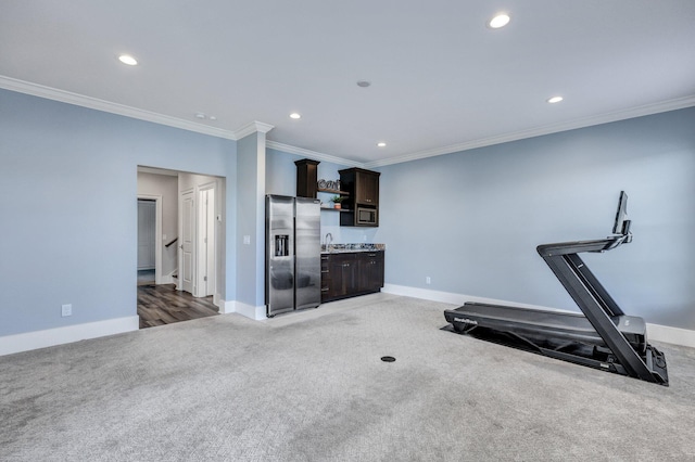 exercise room with wet bar, crown molding, light colored carpet, and recessed lighting