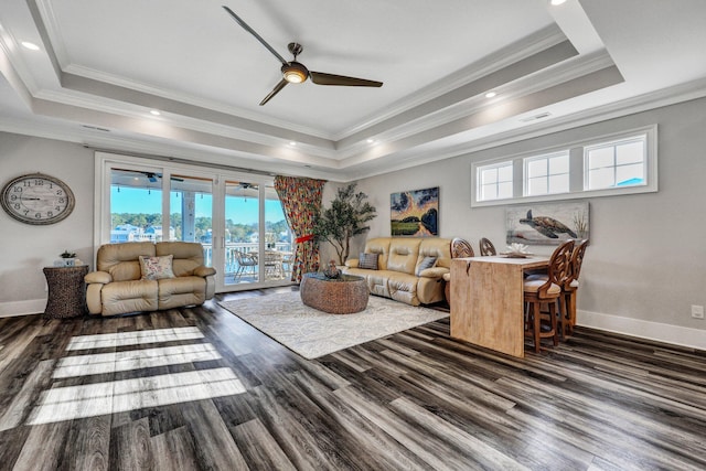 living area featuring a raised ceiling, wood finished floors, baseboards, and ceiling fan
