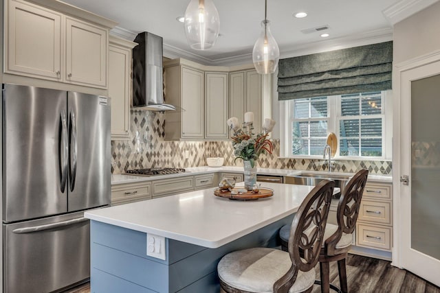 kitchen with light countertops, stainless steel appliances, wall chimney range hood, visible vents, and cream cabinetry