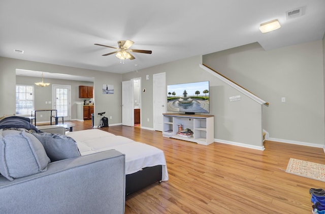 living room featuring ceiling fan with notable chandelier and hardwood / wood-style floors