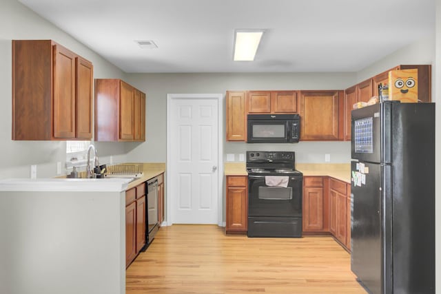 kitchen with sink, black appliances, and light hardwood / wood-style floors