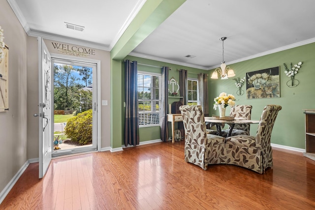 dining space with a chandelier, wood finished floors, baseboards, and ornamental molding