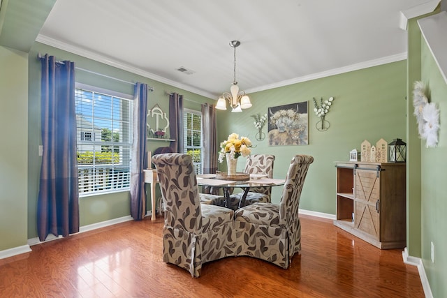dining space featuring wood finished floors, a chandelier, baseboards, and ornamental molding