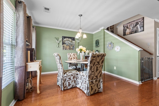 dining area with wood finished floors, baseboards, ornamental molding, and a chandelier
