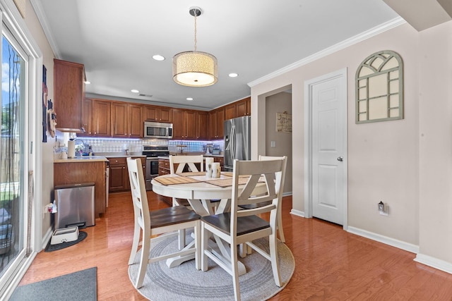 dining room with light wood-style floors, ornamental molding, baseboards, and recessed lighting