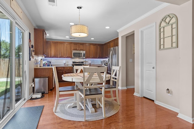 dining area with light wood-type flooring, baseboards, ornamental molding, and recessed lighting