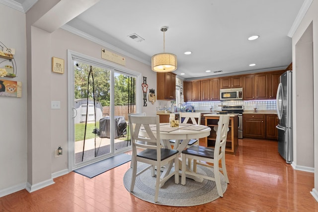 dining space featuring crown molding, light wood-type flooring, baseboards, and recessed lighting