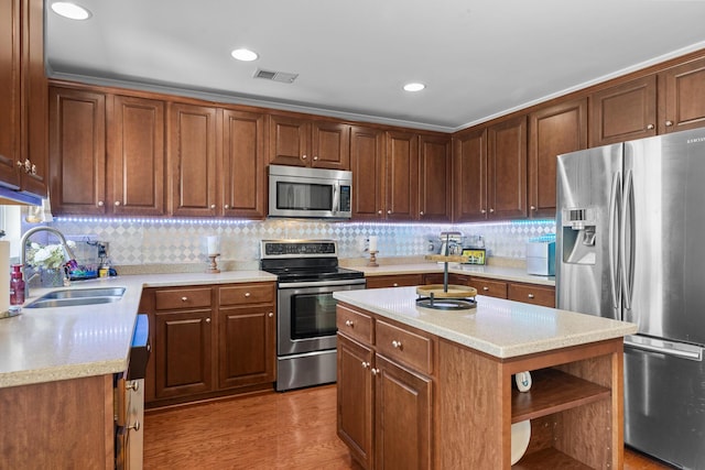 kitchen featuring stainless steel appliances, open shelves, a sink, tasteful backsplash, and a center island