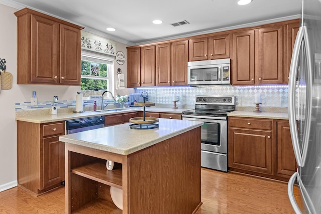 kitchen with stainless steel appliances, open shelves, ornamental molding, a sink, and light wood-style floors