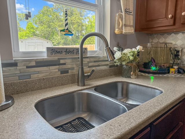 kitchen view of a sink, tasteful backsplash, light countertops, and brown cabinetry