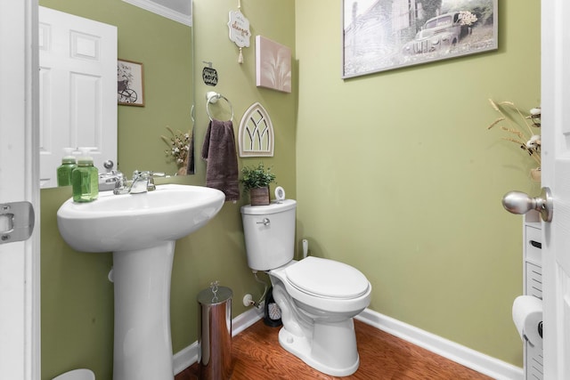 bathroom featuring toilet, wood finished floors, baseboards, and a sink