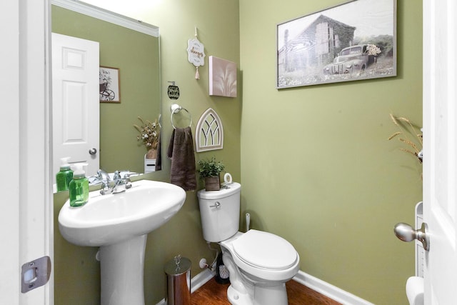 half bath with toilet, baseboards, and a sink