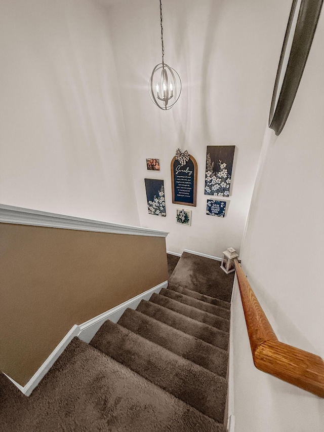 stairs featuring a chandelier, carpet floors, and baseboards