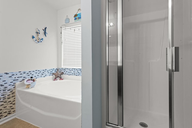 bathroom with a shower stall, a bath, tile patterned floors, and tile walls