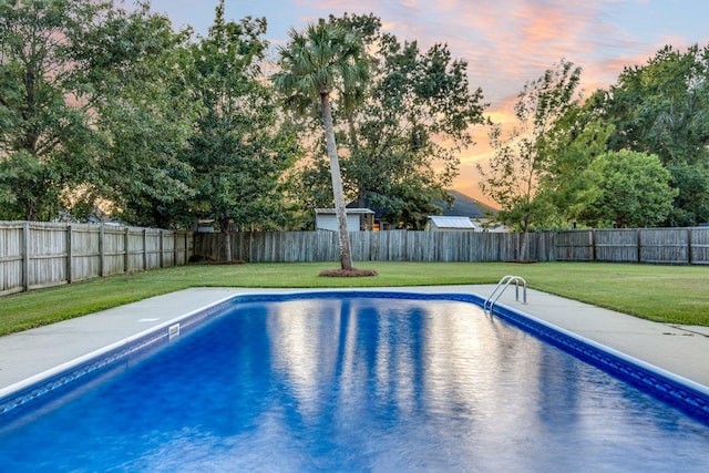 pool at dusk featuring a yard