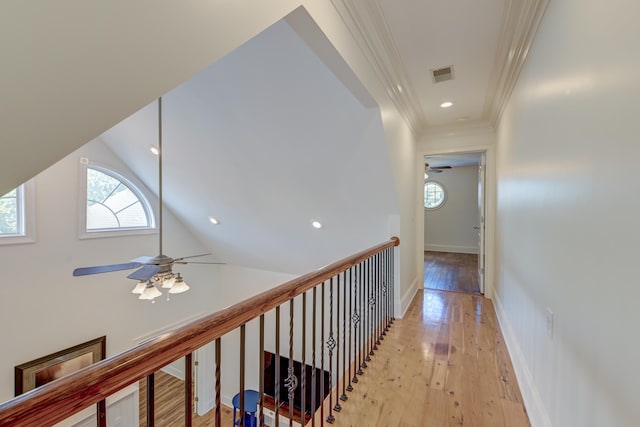 hall featuring vaulted ceiling, ornamental molding, and light wood-type flooring