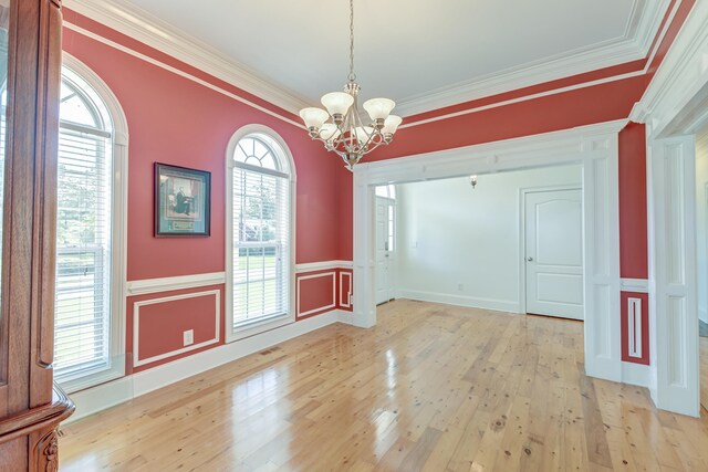 interior space with ornamental molding, light hardwood / wood-style floors, a notable chandelier, and a healthy amount of sunlight